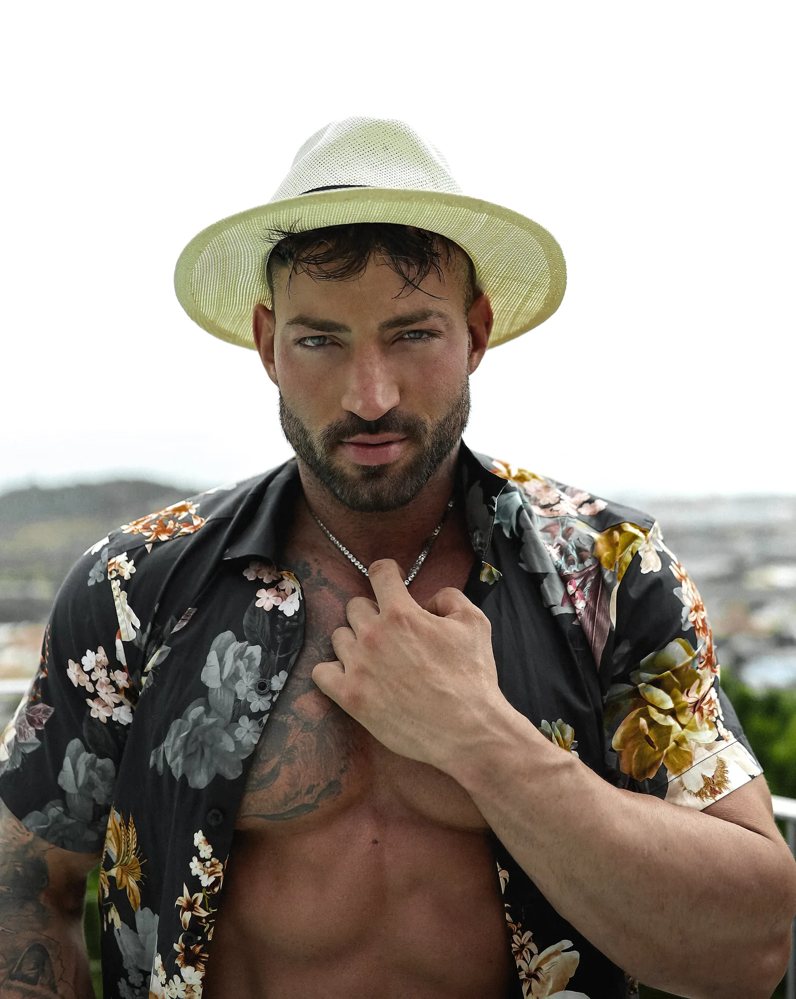 Maximo Garcia com chapéu panamá e camisa floral, olhando diretamente para a câmera